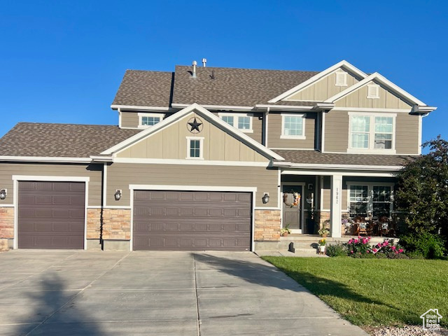 Craftsman house with driveway, a porch, a front yard, and board and batten siding