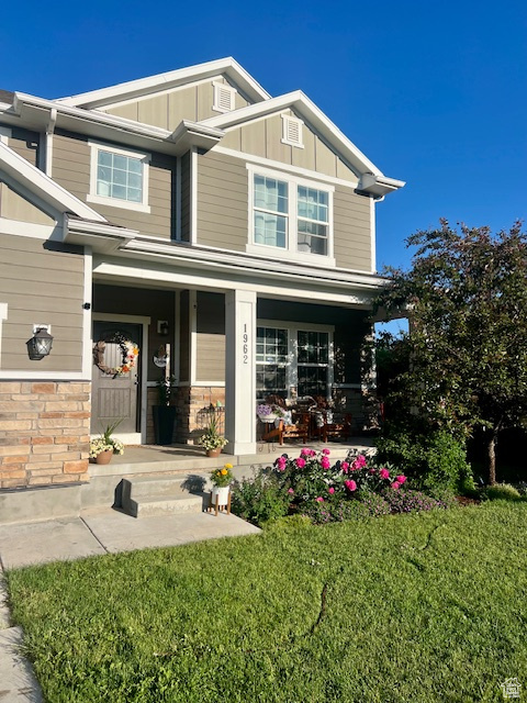 View of front of house with board and batten siding, covered porch, and a front lawn