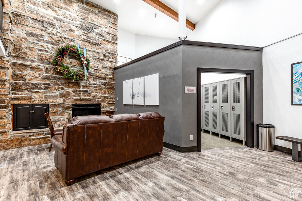 Living room with wood finished floors, beamed ceiling, a fireplace, and high vaulted ceiling