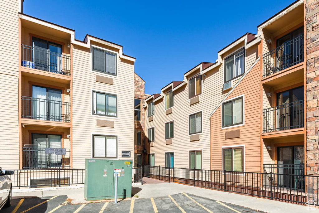 View of building exterior with uncovered parking and fence