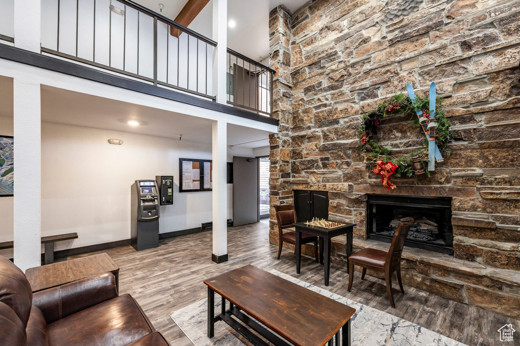 Living room featuring wood finished floors, a fireplace, baseboards, and a towering ceiling