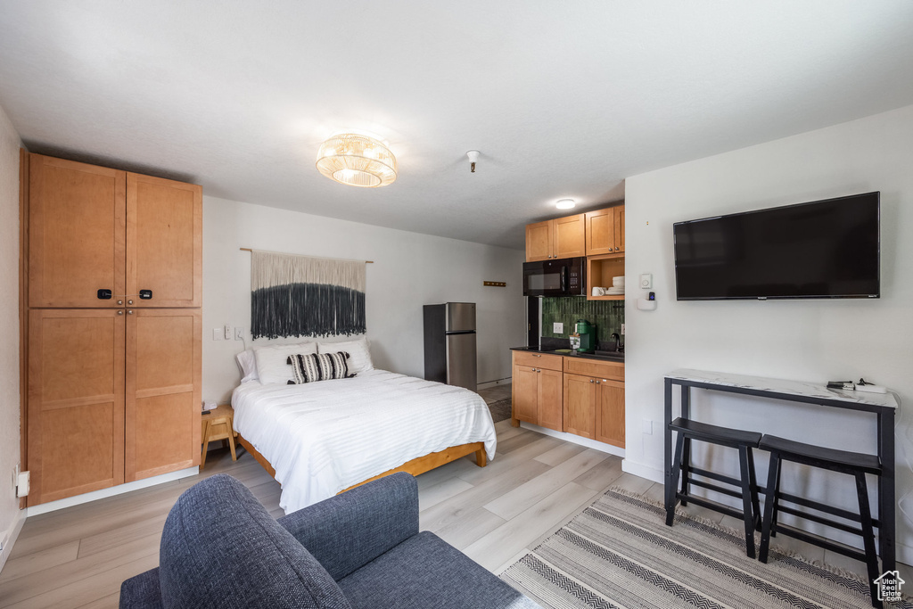Bedroom featuring light wood-style flooring and freestanding refrigerator