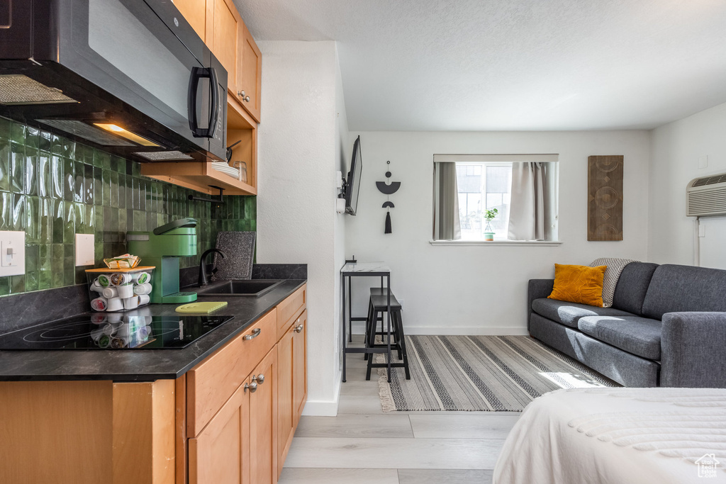 Interior space featuring open floor plan, dark countertops, black appliances, decorative backsplash, and a sink