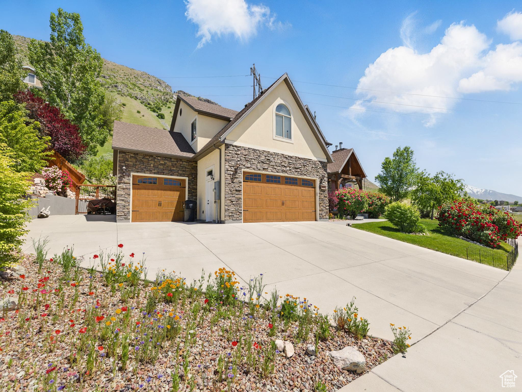 View of front of house with stucco siding, stone siding, concrete driveway, and an attached garage