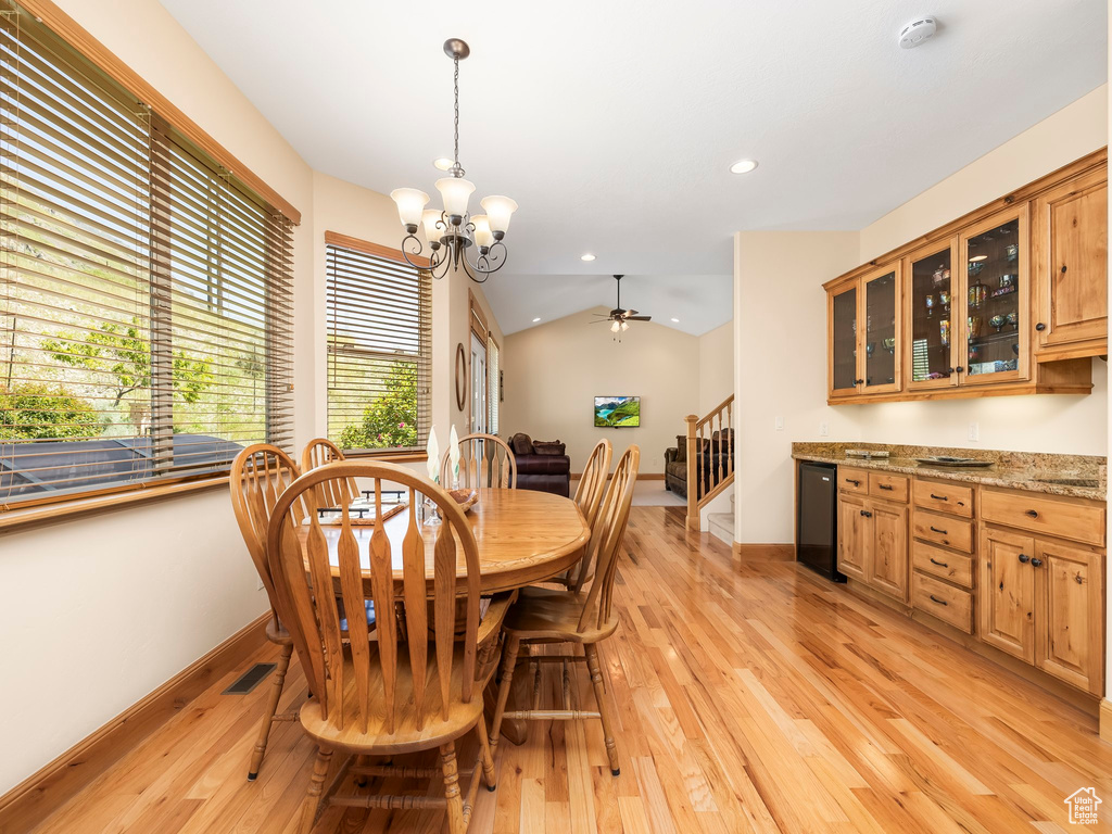 Dining space with stairs, light wood-type flooring, a chandelier, a ceiling fan, and recessed lighting