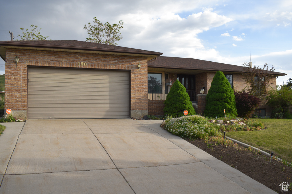 View of front of property featuring brick siding, driveway, a garage, and a front yard