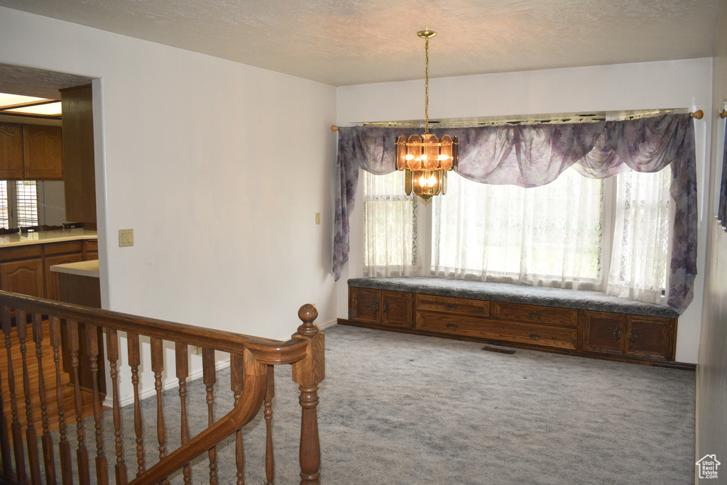 Carpeted dining space with a chandelier and a textured ceiling