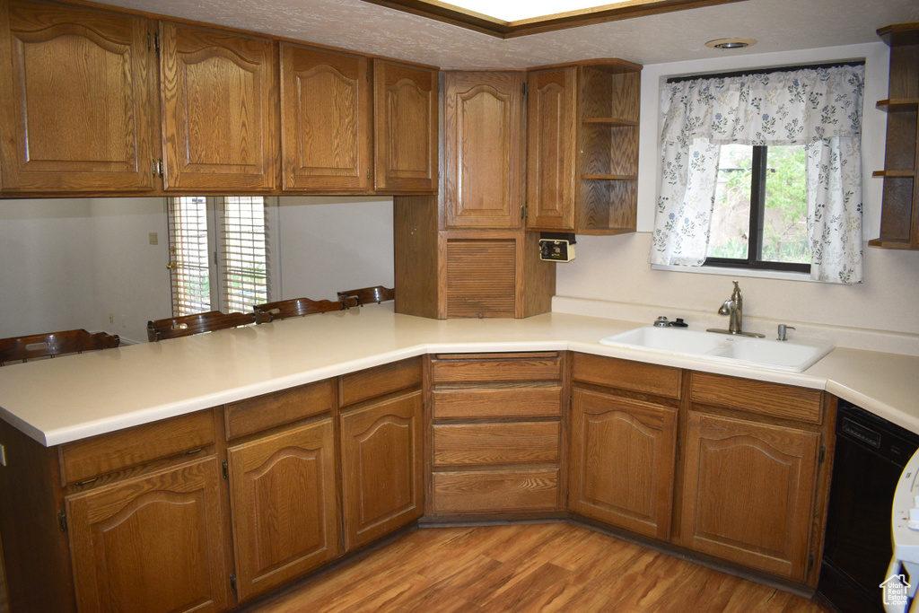 Kitchen with open shelves, a peninsula, black dishwasher, brown cabinets, and light wood-style floors