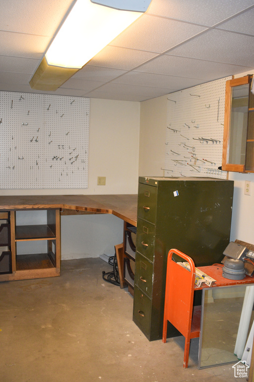 Home office featuring a workshop area, a drop ceiling, and concrete flooring