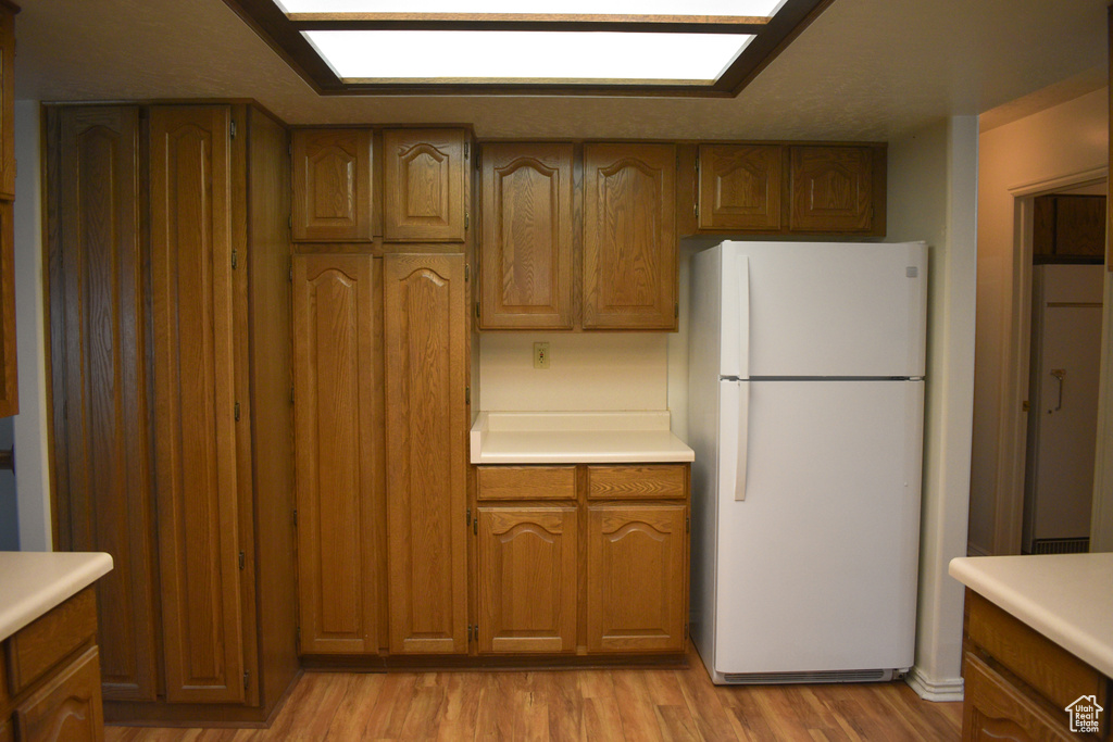 Kitchen featuring freestanding refrigerator, light countertops, light wood-style floors, and brown cabinets