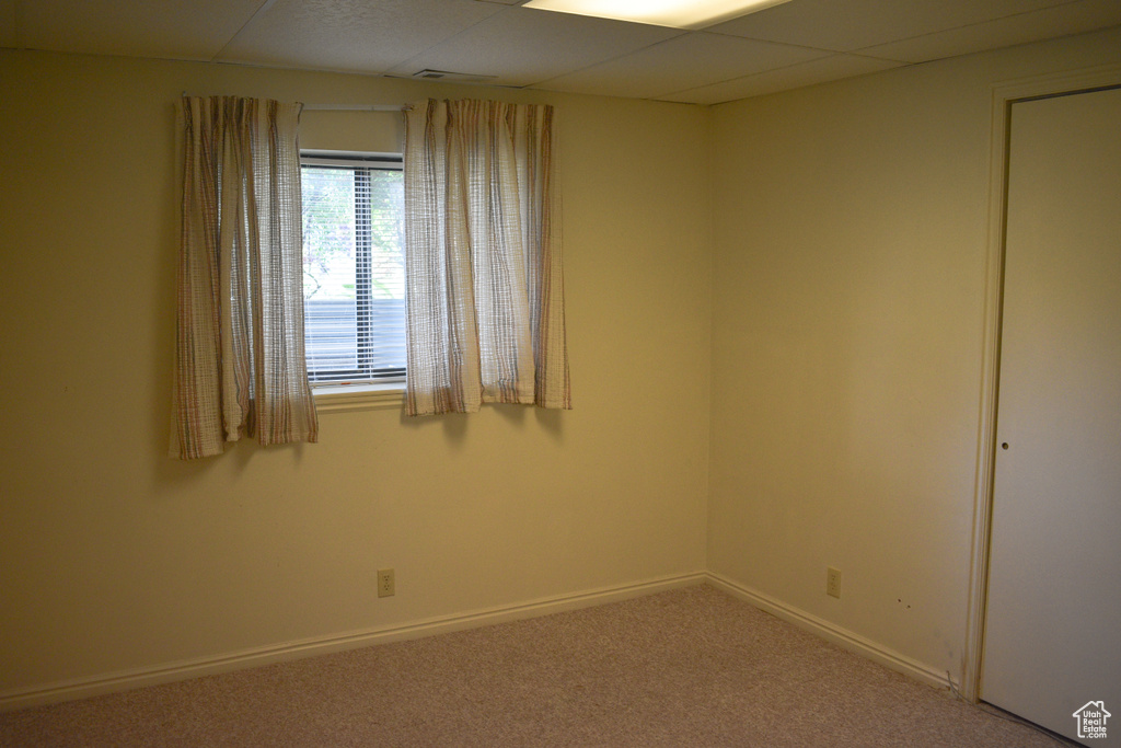 Carpeted spare room with a drop ceiling and baseboards