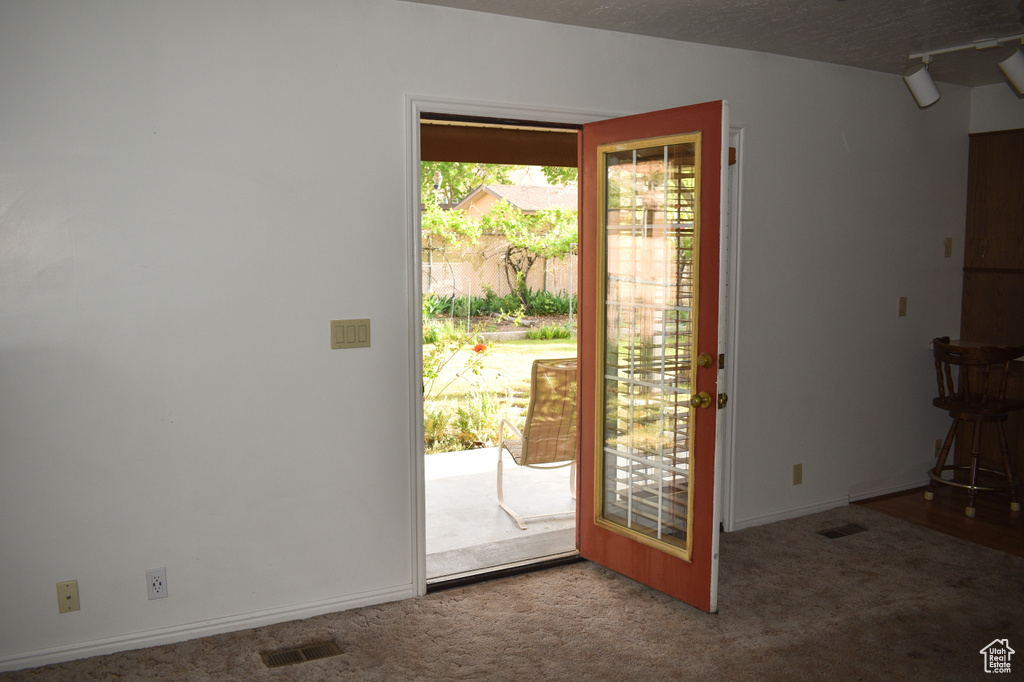 Doorway to outside with carpet and baseboards