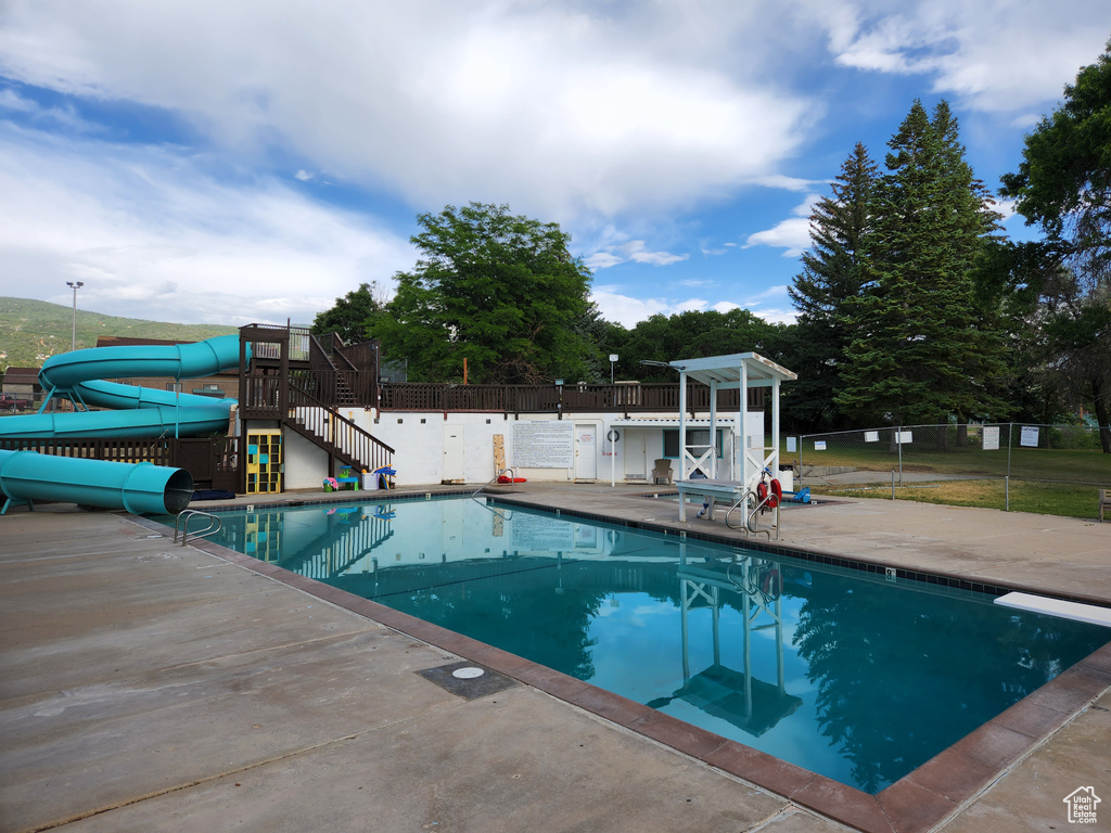 Pool featuring fence, a water slide, a patio, and a diving board