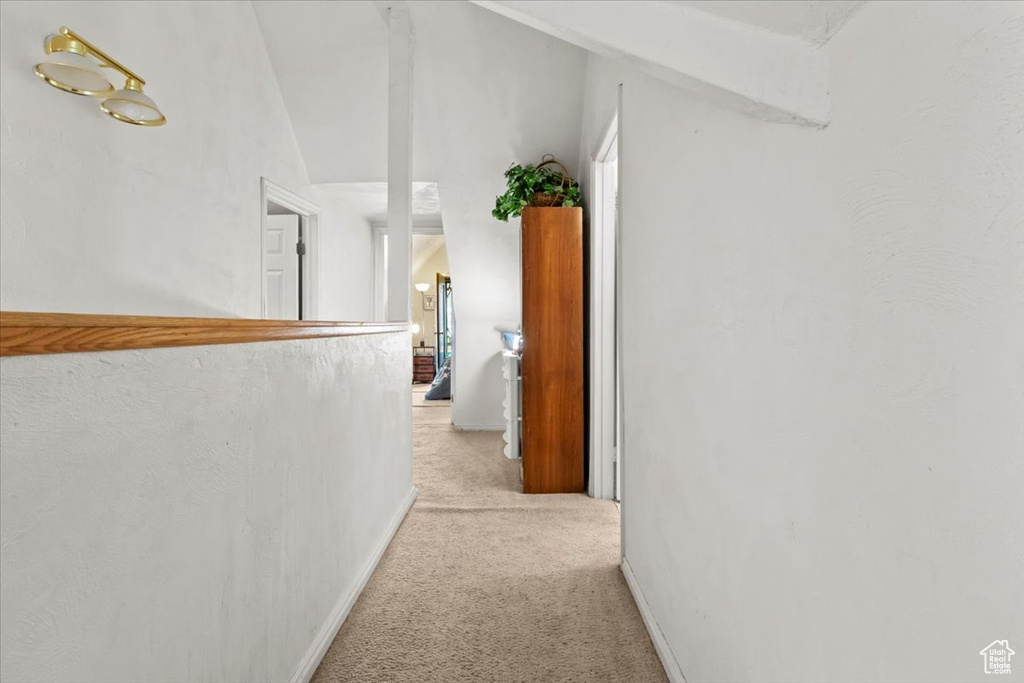 Corridor featuring baseboards and light colored carpet