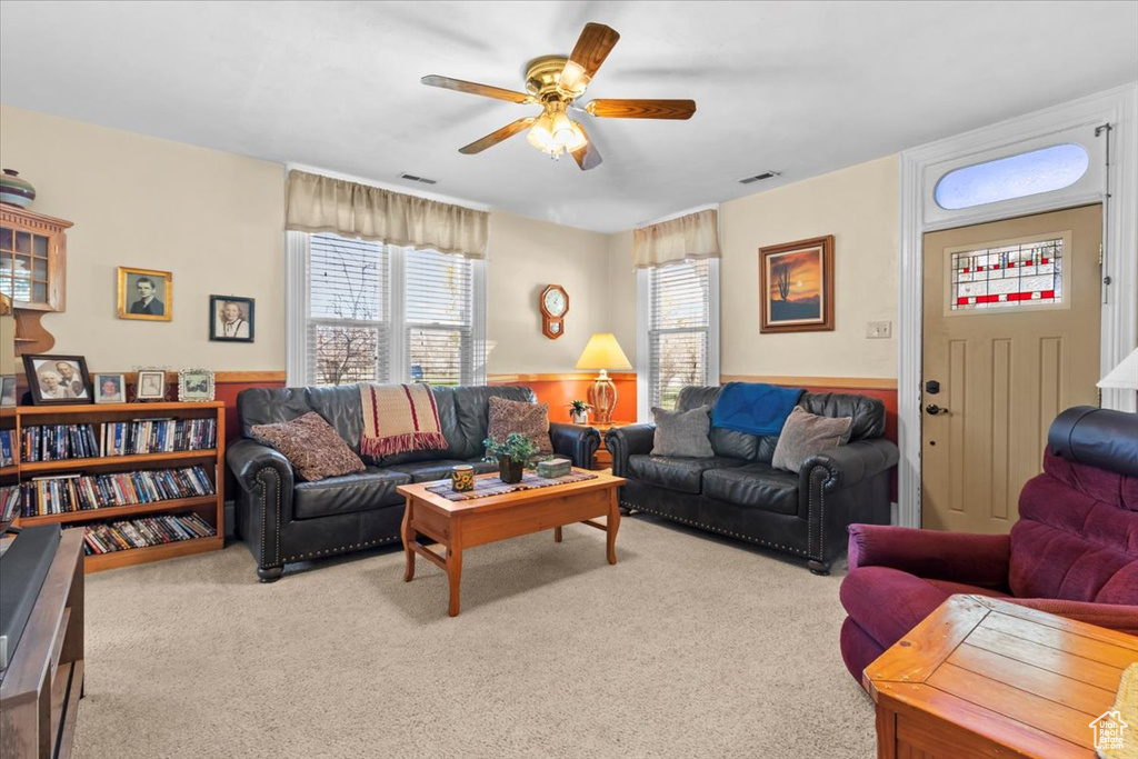 Carpeted living room with visible vents and ceiling fan