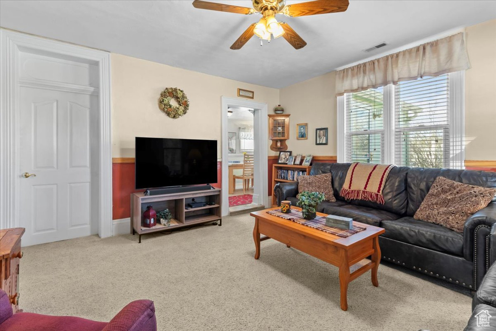 Living area with carpet flooring, visible vents, and ceiling fan