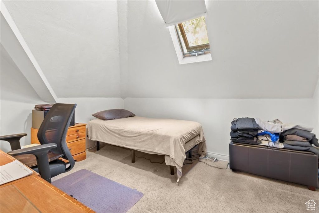 Bedroom with vaulted ceiling with skylight and carpet
