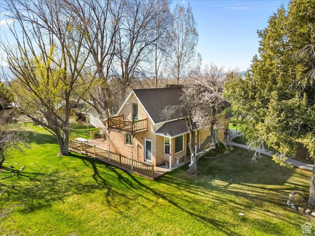 Back of house with brick siding, a deck, and a yard