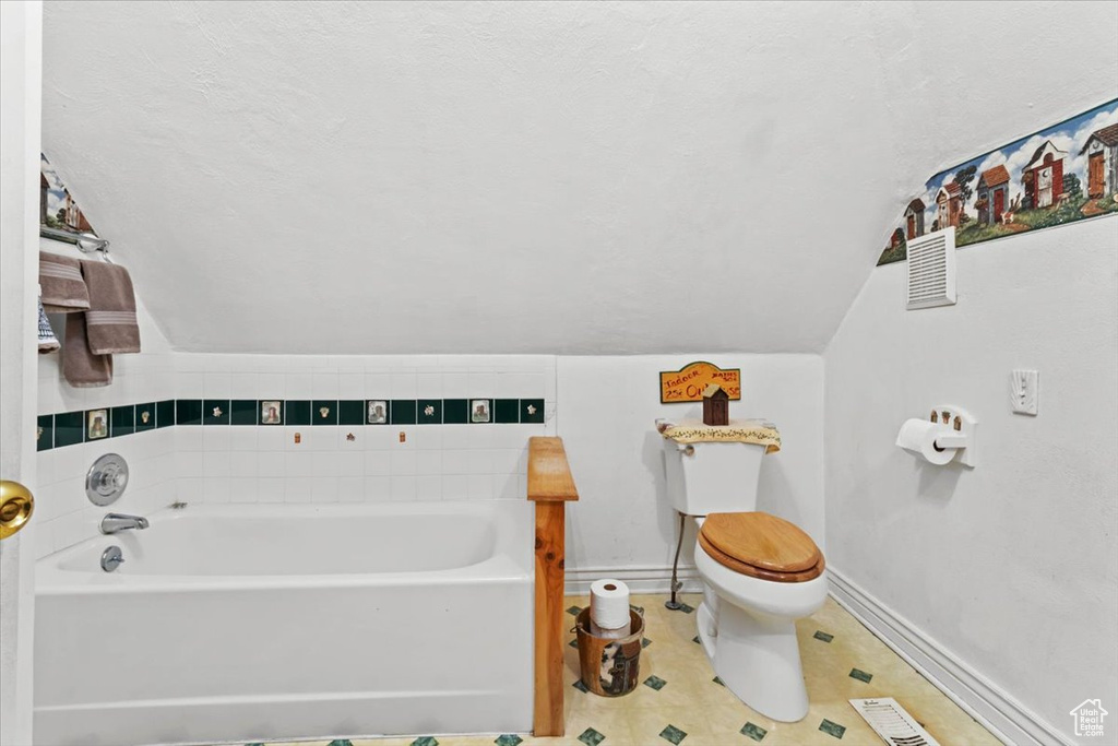 Full bathroom featuring a garden tub, vaulted ceiling, visible vents, toilet, and baseboards