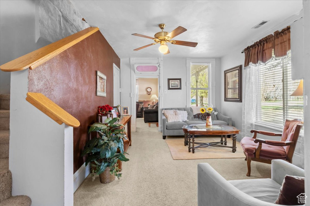 Living room featuring visible vents, a ceiling fan, and carpet floors
