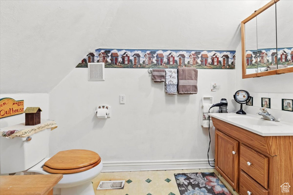 Bathroom with vanity, tile patterned floors, toilet, visible vents, and lofted ceiling
