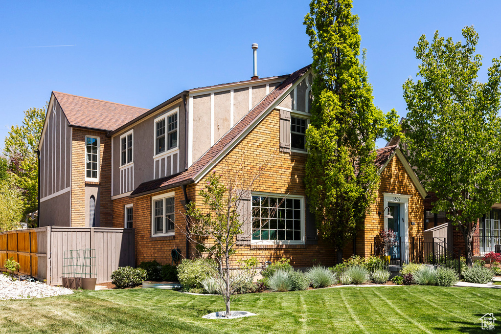 Back of property featuring a shingled roof and brick siding