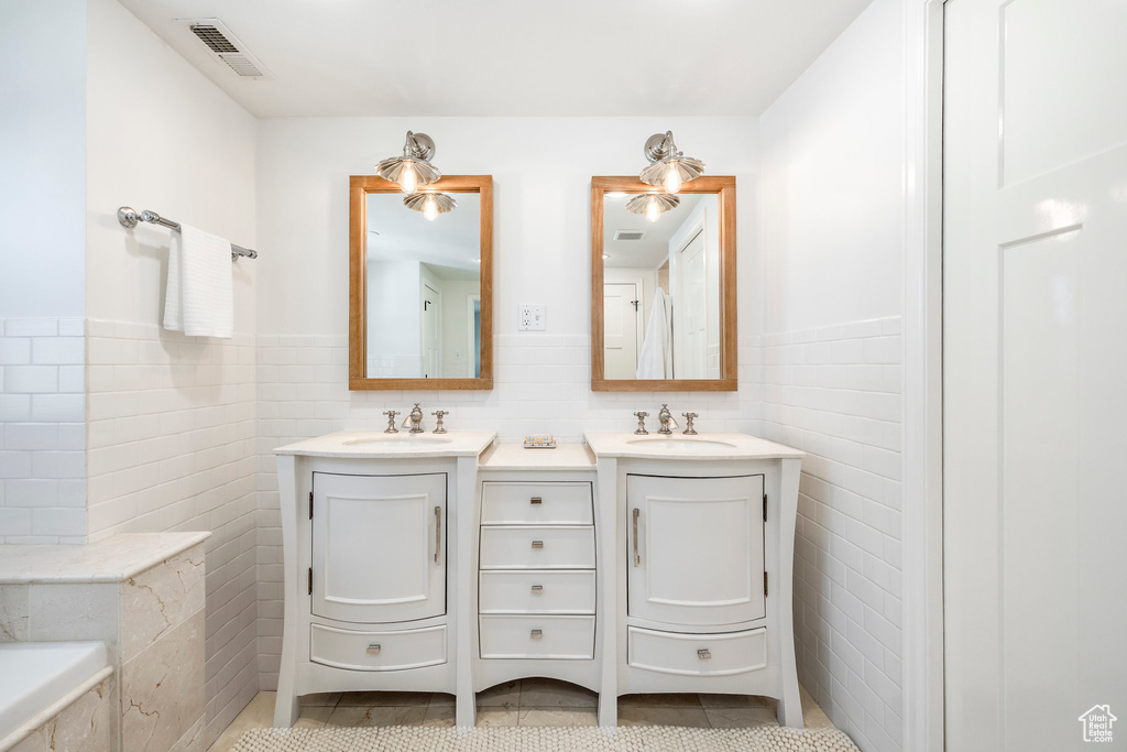 Bathroom with vanity, tile patterned flooring, wainscoting, and tile walls