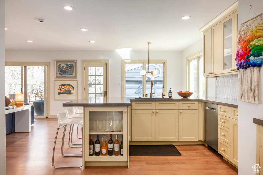 Kitchen with stainless steel dishwasher, a peninsula, a wealth of natural light, and a sink