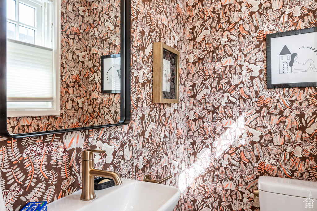 Interior details with a sink, toilet, and wallpapered walls