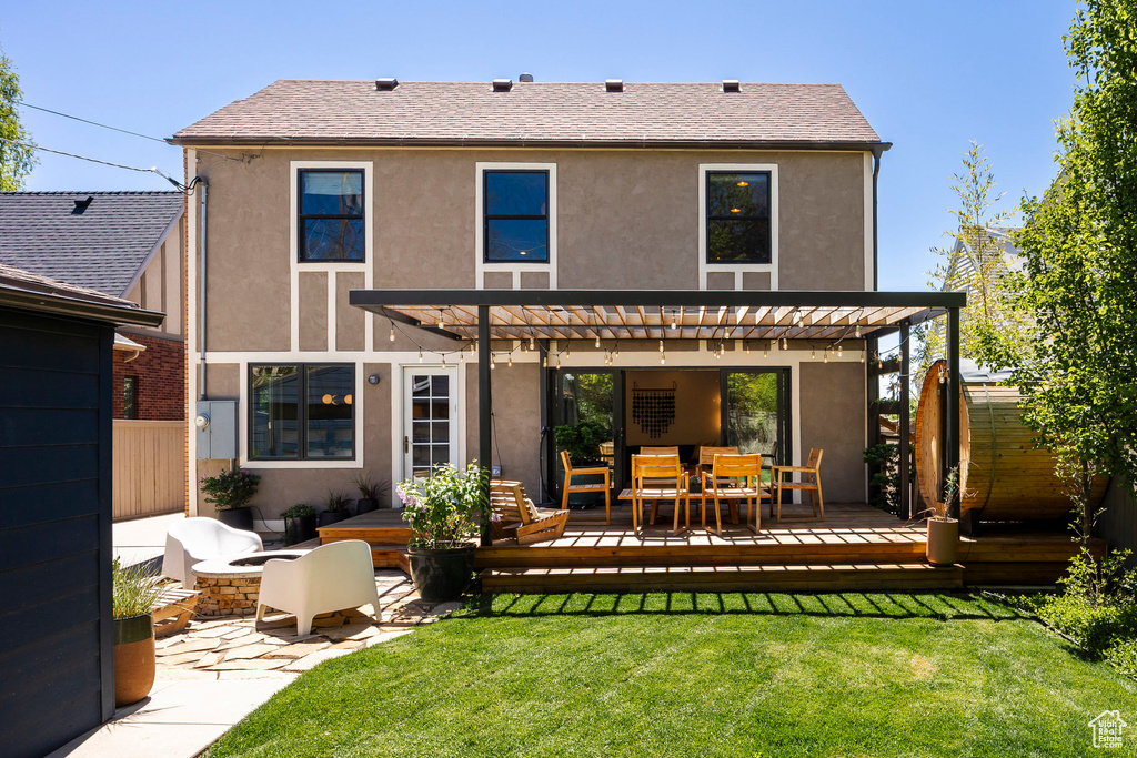 Rear view of property featuring a deck, stucco siding, a pergola, and outdoor dining space