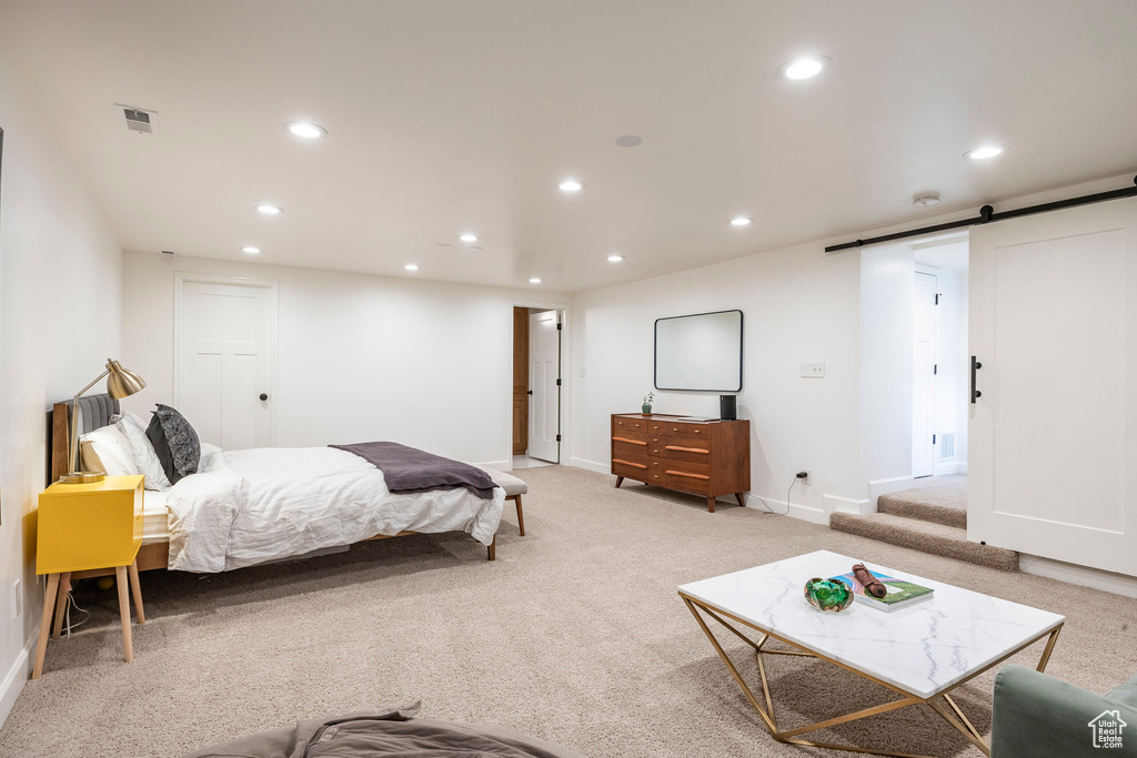 Bedroom featuring recessed lighting, light colored carpet, and a barn door