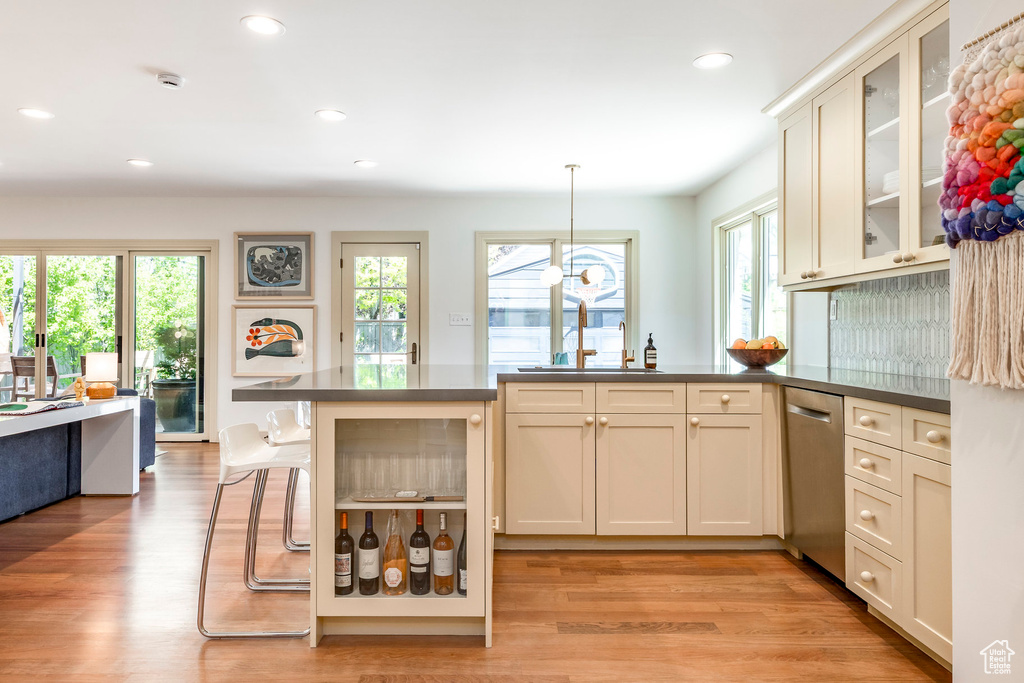 Kitchen with dishwasher, a peninsula, dark countertops, glass insert cabinets, and recessed lighting