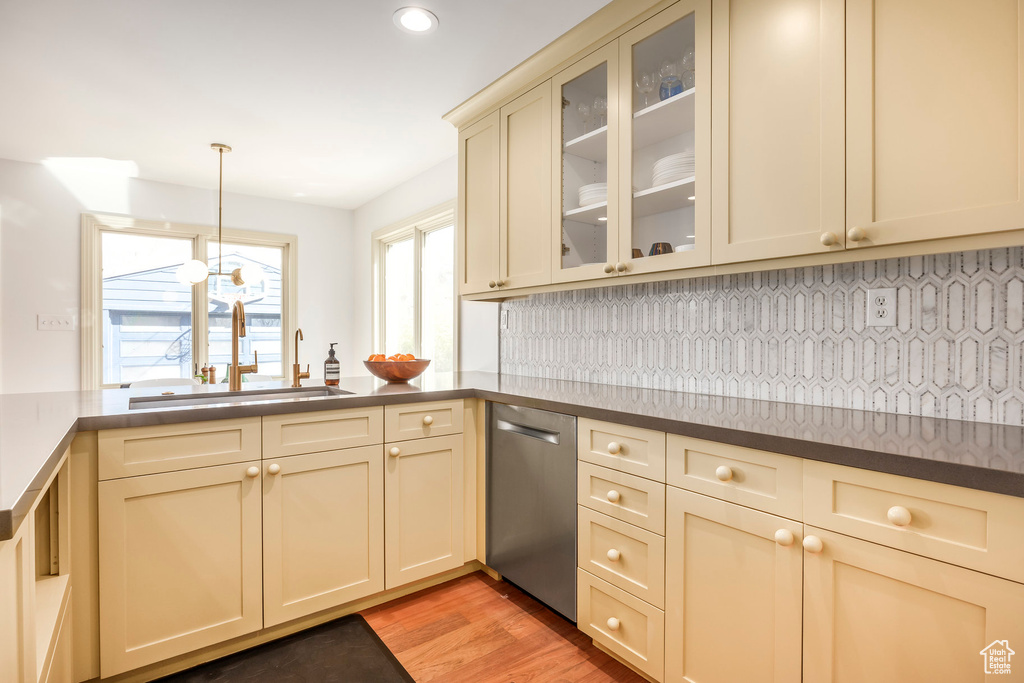 Kitchen featuring decorative light fixtures, stainless steel dishwasher, light wood-type flooring, a sink, and cream cabinetry