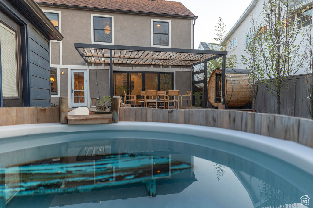 Rear view of house with fence private yard, an outdoor pool, stucco siding, a shed, and an outbuilding