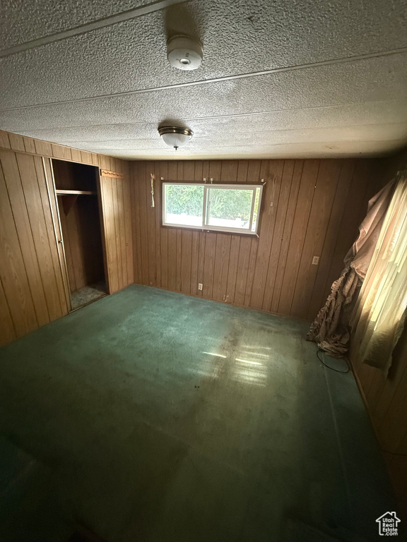 Unfurnished bedroom with wooden walls and carpet flooring