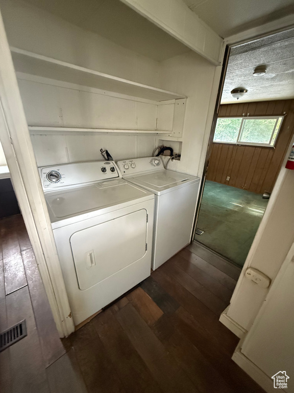 Laundry room with washer and clothes dryer and dark wood finished floors