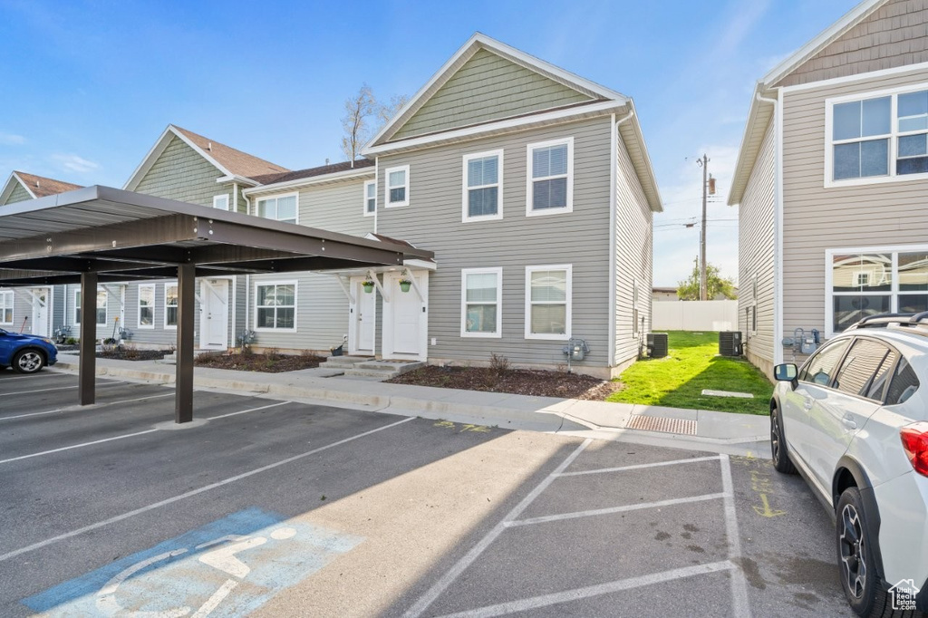 View of front of house featuring central air condition unit and covered and uncovered parking