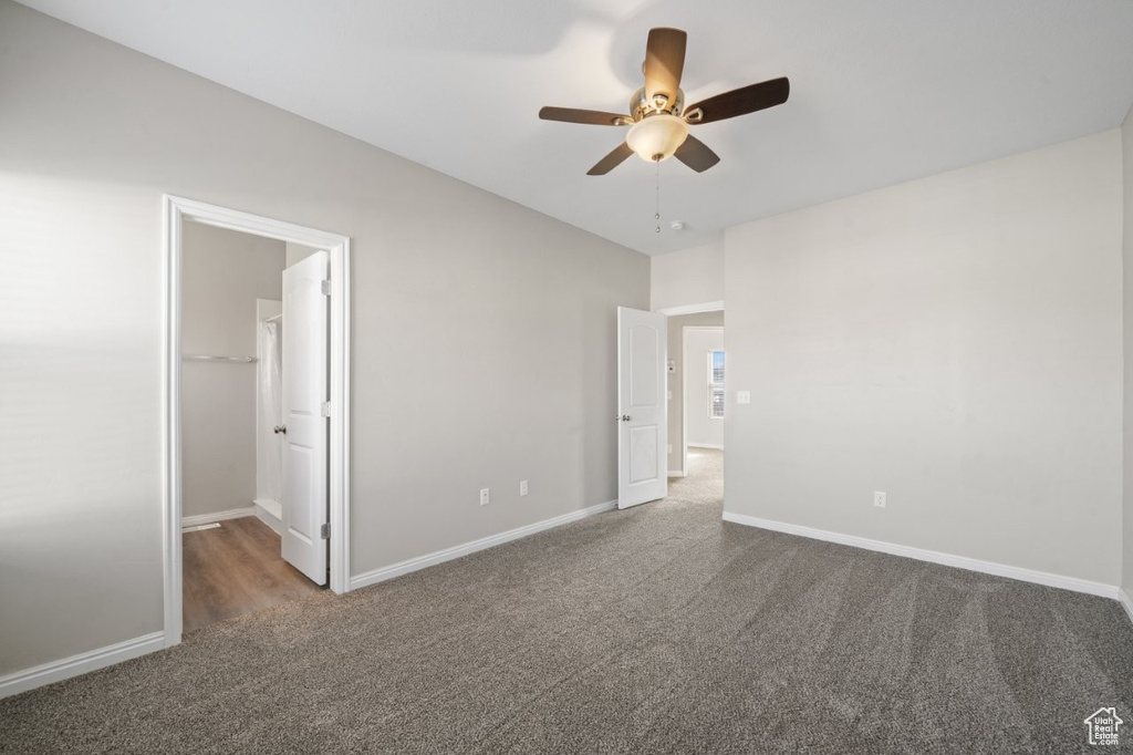 Unfurnished bedroom featuring a closet, baseboards, ceiling fan, carpet floors, and a walk in closet