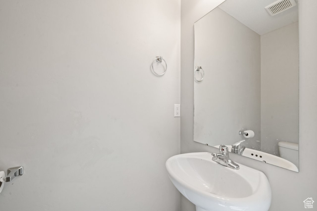 Bathroom featuring toilet, a sink, and visible vents