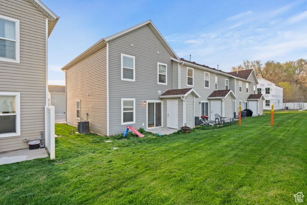 Rear view of property with cooling unit, a patio, and a lawn