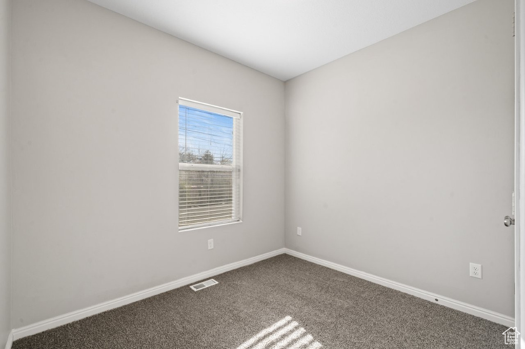 Carpeted empty room featuring baseboards and visible vents