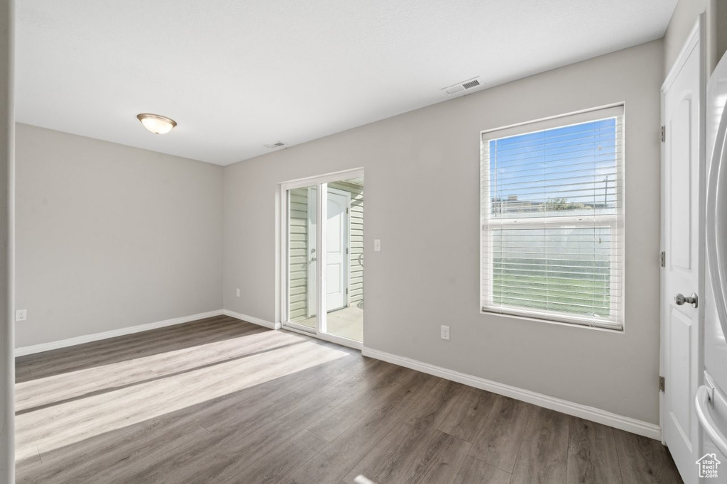Empty room featuring wood finished floors, baseboards, and visible vents