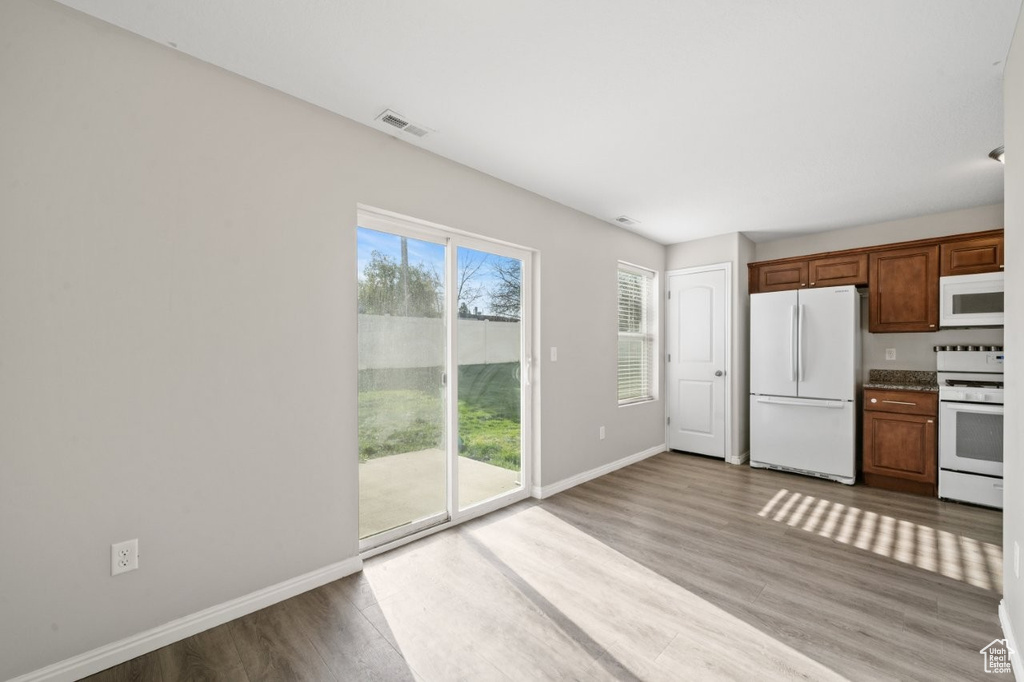 Kitchen featuring wood finished floors, baseboards, white appliances, and a wealth of natural light