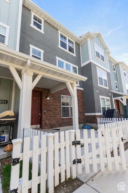 Multi unit property with brick siding, a fenced front yard, board and batten siding, and stucco siding