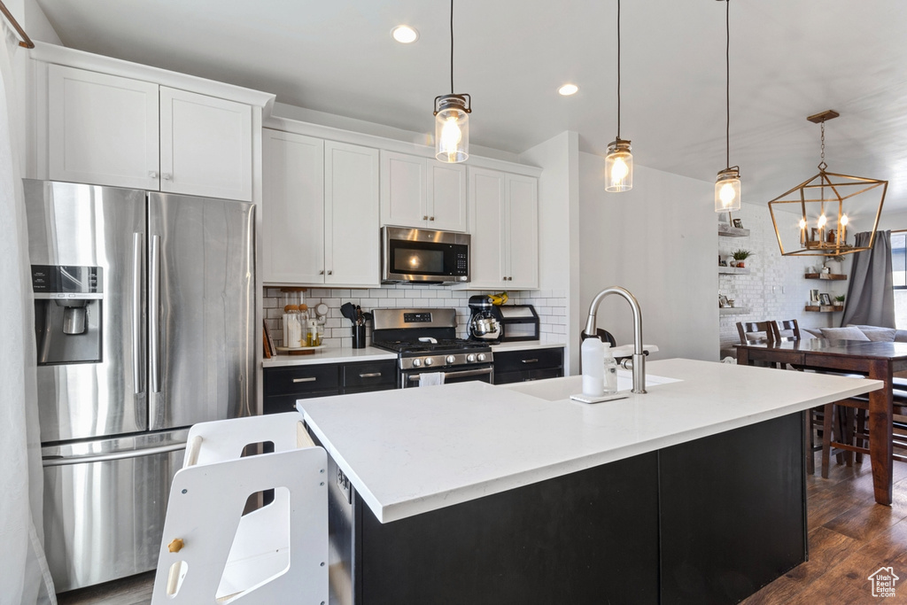 Kitchen with stainless steel appliances, a sink, recessed lighting, a chandelier, and light countertops