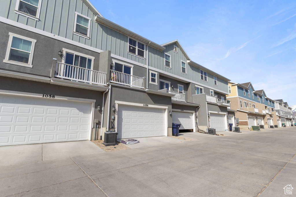 View of building exterior featuring a residential view, an attached garage, central AC, and concrete driveway