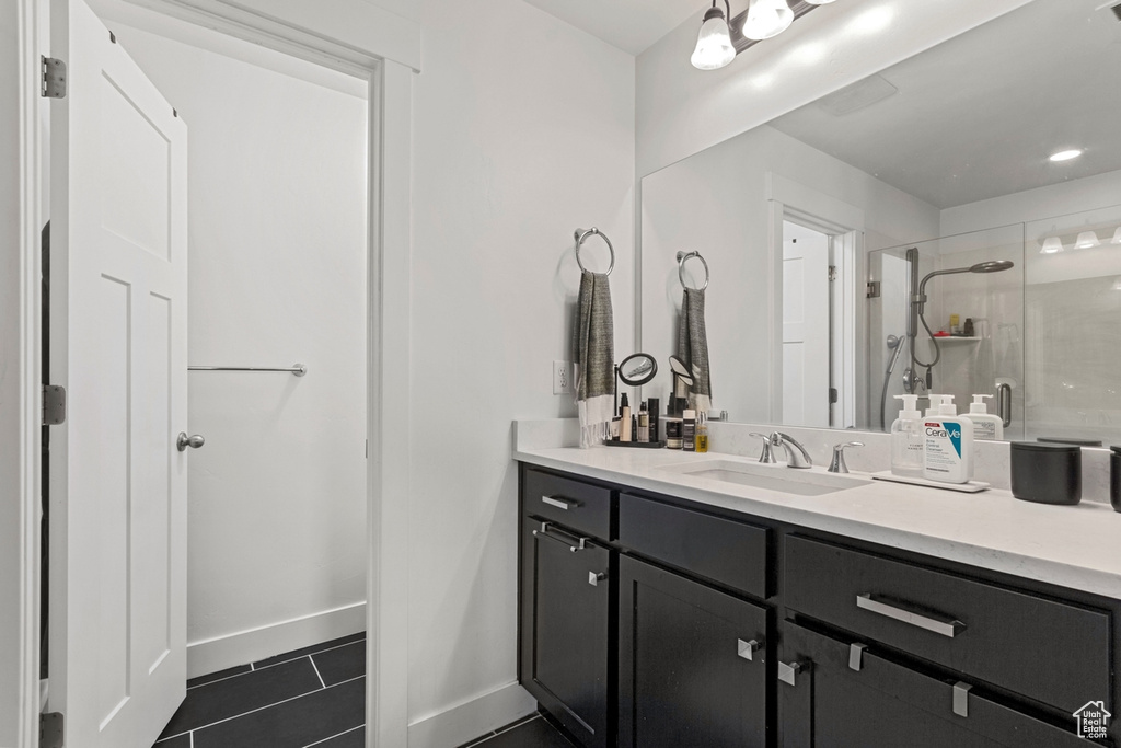 Bathroom featuring a shower stall, tile patterned floors, vanity, and baseboards