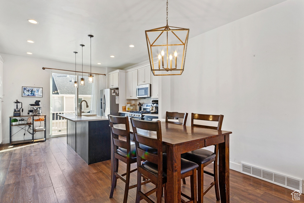 Dining room with dark wood-style flooring, a chandelier, recessed lighting, and baseboards