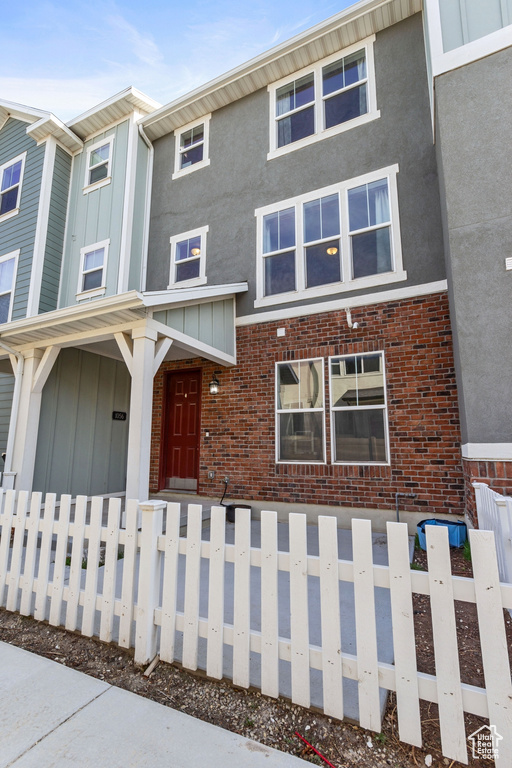 Multi unit property featuring board and batten siding, a fenced front yard, and stucco siding