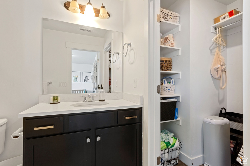 Bathroom with toilet, vanity, and baseboards